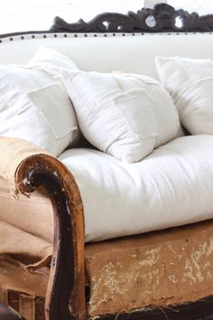 an old couch with white pillows on it