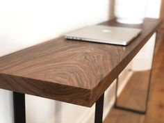 a laptop computer sitting on top of a wooden table next to a white wall in a room