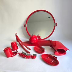 a red vanity mirror sitting on top of a table next to other bathroom items and accessories