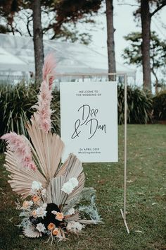 a sign that is sitting in the grass near some flowers and plants on the ground