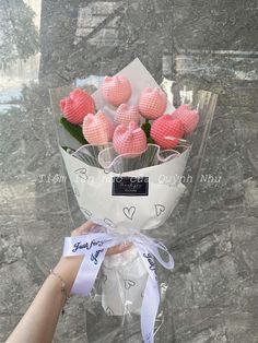 a hand holding a bouquet of pink flowers