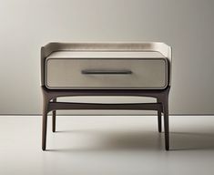 a modern nightstand with an upholstered drawer on one side and a closed drawer on the other