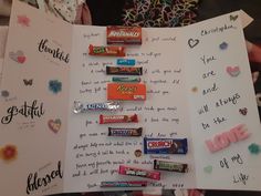 an open book with candy on it and handwritten notes attached to the front cover