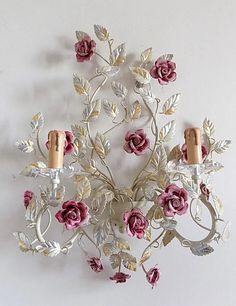 a decorative wall light with pink flowers and two candles on the top of each candle holder