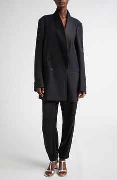 Van Noten's unique take on the tuxedo jacket means an oversized cut that draws attention to what makes it the pinnacle of formalwear, such as the balance struck between matte and sheen via satin covering the buttons, pocket openings and smoothly curved lapels. This style was represented in the Belgian designer's fall '24 runway show. 36" length (size Small) Double-breasted button closure Shawl collar Four-button cuffs Chest welt pocket; front welt pockets Lined 82% wool, 10% silk, 8% polyester D Black Double-breasted Evening Suit, Luxury Black Blazer Dress For Semi-formal Occasions, Luxury Black Blazer Dress For Semi-formal Events, Designer Evening Blazer With Double-breasted Buttons, Tuxedo Style Outerwear With Double Button Closure, Designer Evening Outerwear With Concealed Placket, Evening Tuxedo Suit With Double-breasted Button Fastening, Evening Tuxedo Suit With Double-breasted Button, Evening Double-breasted Tuxedo Suit