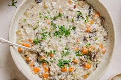 a bowl filled with rice and carrots on top of a white table next to a spoon