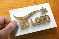 a hand holding up a business card with the word 3d logo printed in gold and silver