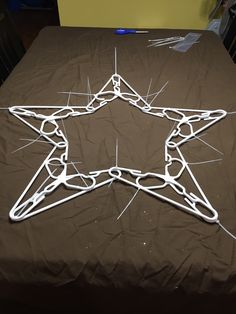 a star made out of wire sitting on top of a brown bed cover with white thread