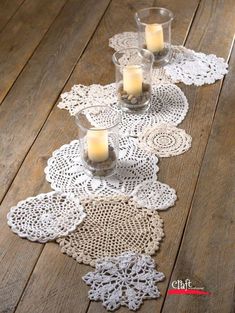 two candles are sitting on doily next to each other