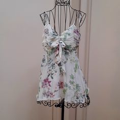 Brand New Hale Bob Floral Camisole Summer Top. Has A Bow In The Front And Spaghetti Straps That Tie So Therefore They Are Adjustable. Top Is Approx. 22 Inches Long From Top To Bottom Hem. Front Of Top Is Handkerchief Bottom, So Not Straight Across. Size Medium. Never Worn. Laying Flat, It Measures 17 And A Half Inches Across The Bust. Fits A 36-In Bust Or Smaller. Floral Print Cami Camisole For Party, Floral Print Camisole With Spaghetti Straps For Parties, Party Camisole With Floral Print, Summer Party Camisole With Floral Print, Summer Party Floral Print Camisole, White Floral Print Tank Top For Party, Feminine Beach Camisole With Floral Print, Purple Floral Print Summer Tank Top, Floral Print Spaghetti Straps Tank Top For Party