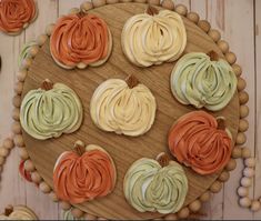 cupcakes with frosting and pumpkin decorations on a wooden platter