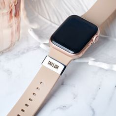 an apple watch sitting on top of a marble counter next to a glass vase with flowers