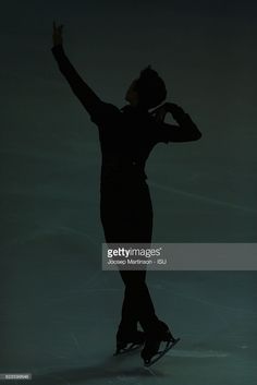 the figure skater is silhouetted against a dark background as she performs in an ice skating competition