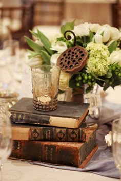 a table topped with books and vases filled with flowers on top of each other