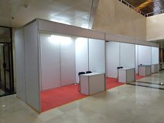 an empty room with several cubicles on the floor and red carpeted flooring