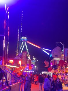 people are walking around an amusement park at night