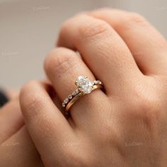 a woman's hand with a diamond ring on top of her finger and the other hand holding it