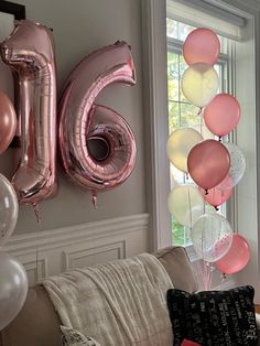 balloons and streamers in the shape of numbers are hanging on the wall next to a couch