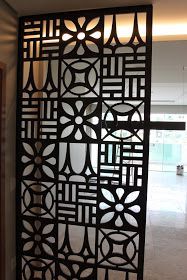 an intricately designed metal screen in the middle of a room with white walls and flooring