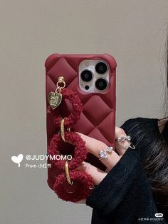 the woman is holding her phone case with pom poms