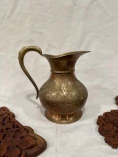 an antique brass pitcher and coasters on a white tablecloth