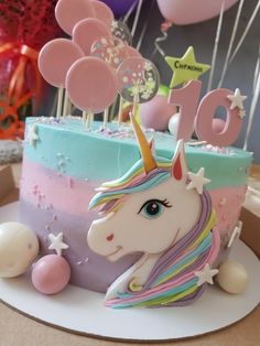 a birthday cake decorated with unicorns and balloons