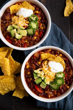 two bowls filled with chili, cheese and tortilla chips