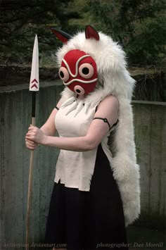 a woman in a costume holding a stick and wearing a mask with horns on her head