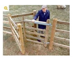 an old man standing in front of a wooden fence with sheep behind it and looking over the gate