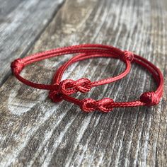 a red string bracelet on top of a wooden table