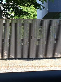 a man riding a skateboard down the side of a street next to a tall wooden fence