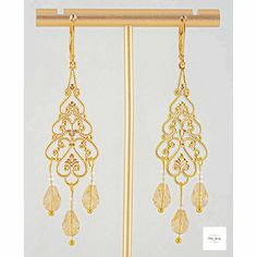 Add some radiance and enchantment to your style with these stunning yellow champagne filigree earrings! The sparkling yellow champagne-colored glass teardrop beads are perfectly accented by shimmery white glass beads, all set in intricate gold-plated filigree and lever backs. These dangling earrings, measuring 2.75 inches, will definitely catch attention. Elevate any ensemble with these gorgeous yellow glass and gold filigree earrings. Elegant Gold Long Drop Chandelier Earrings, Festive Gold Earrings With Gold Beads, Elegant Linear Earrings With Dangling Beads For Party, Gold Earrings With Beads For Celebration, Elegant Danglers With Dangling Beads For Celebration, Elegant Gold Beaded Drop Earrings, Elegant Gold Beads Drop Earrings, Elegant Beaded Teardrop Crystal Earrings, Elegant Earrings With Gold Beads