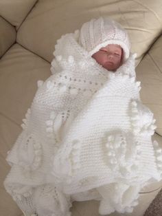 a baby wrapped in a white crochet blanket