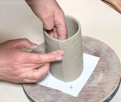 someone is making a vase out of clay on a table with a paper plate next to it