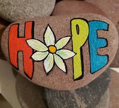 a rock with the word hope painted on it and a flower in the center surrounded by rocks