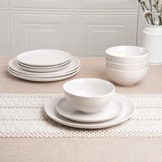 a table set with white dishes and place settings