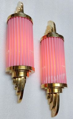 two pink and gold sconces mounted on a white wall next to each other