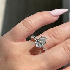 a woman's hand with a ring on top of her finger and pink manicured nails