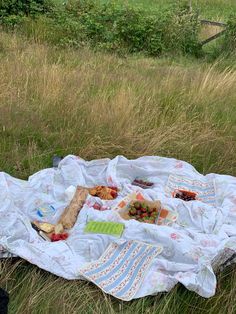 a picnic blanket with food on it laying in the grass