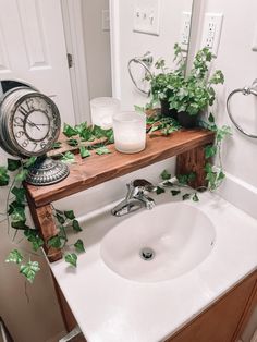 a bathroom sink with plants on the counter and a mirror above it that has a clock