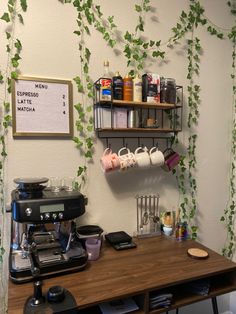 a coffee maker sitting on top of a wooden table next to a shelf filled with cups