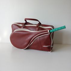 a red leather duffel bag with a green pencil sticking out of the top handle