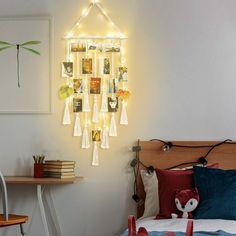 a room with a bed, desk and pictures on the wall above it is lit up by string lights