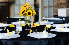 sunflowers in a vase on a table with white napkins and place cards