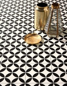 a black and white tiled floor with two vases on the ground next to it