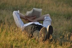 a person laying in the grass reading a book