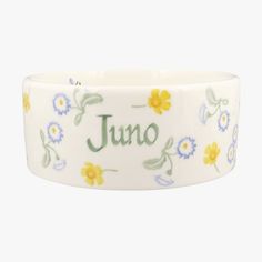 a white bowl with yellow flowers and the word juno written in cursive writing