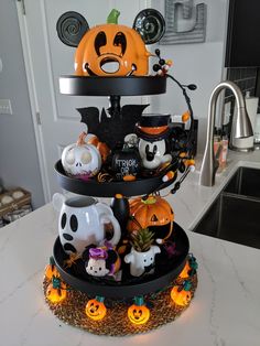 a three tiered halloween cake with pumpkins and ghost figurines on it