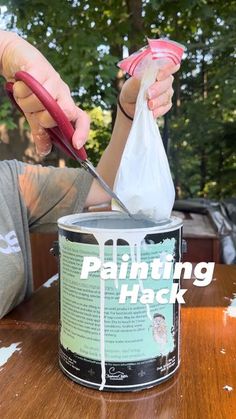 a person holding a pair of scissors in front of a paint can with the words painting hack on it