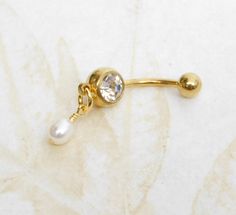 Dainty White Pearl Belly Ring 14g surgical steel belly ring features a small hand wire wrapped white freshwater pearl dangle. You choose from gold or silver. *Please note this is a small dainty pearl, pearl measures approximately 4mm in diameter by 6mm long. Belly ring measures 1 1/4 inches long total length. Barbell is 14g surgical steel or gold-plated surgical steel. For Belly Button Rings: https://www.etsy.com/shop/AllAboutClass?section_id=18474235&ref=shopsection_leftnav_1  All body jewelry Adjustable Gold Belly Rings For Wedding, Cute Belly Rings, Bellybutton Piercings, Belly Button Piercing Jewelry, Gold Belly Ring, Belly Button Jewelry, Dangle Belly Rings, Button Rings, Belly Piercing